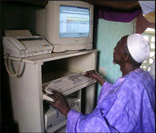 An elderly man operating a desktop computer.