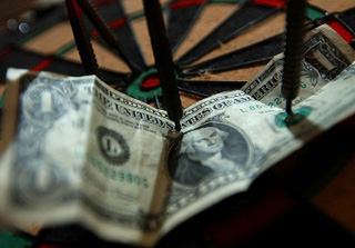 A dollar bill pinned to a dart board. 