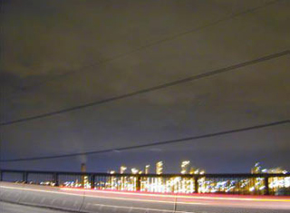 Photo of a city skyline at night, with power lines in the foreground.
