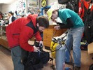 Photograph of scuba instructor Cal Barry assembling all of his gear and helping one of his former students check his regulator for leaks.