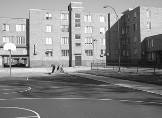 A black and white photo of an apartment building from a basketball court.