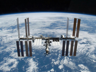 Photograph of the International Space Station with the blue oceans of Earth visible below.