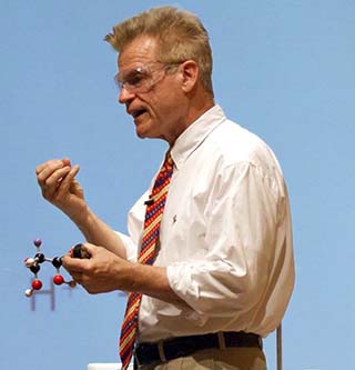 A photo of Dr. John Dolhun, the course instructor, lecturing and holding a molecular model. A photo of Dr. John Dolhun, the course instructor, lecturing and holding a molecular model.