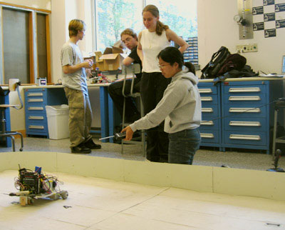 Photo of two students testing their de-mining robot.