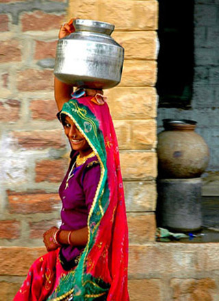 Indian girl carrying a water container on her head.