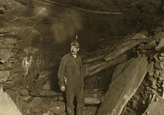 A black and white photo of a miner in a tunnel.