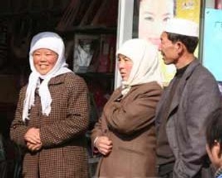 Photo of two Hui women and a man, on a streetcorner.
